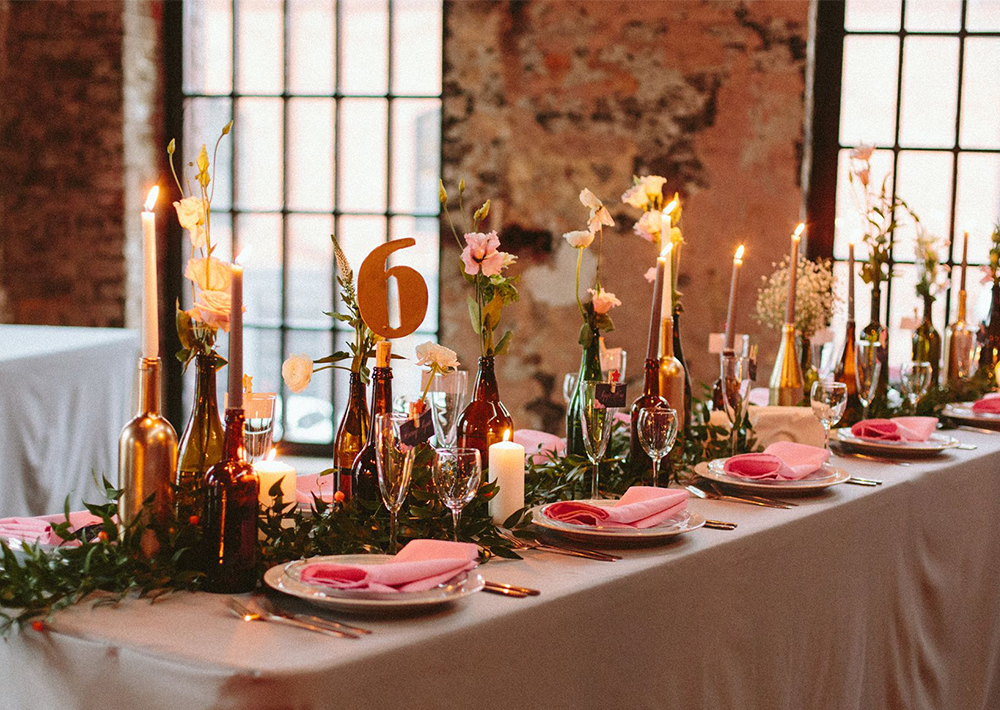 Оформление прямоугольных столов гостей на свадьбу в стиле лофт с цветами и свечами в бутылках